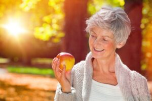 happy senior woman with apple