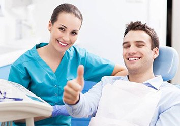 Smiling man in dental chair giving thumbs up