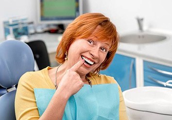 Senior woman in dental chair pointing at smile