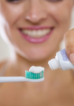 woman putting toothpaste on toothbrush