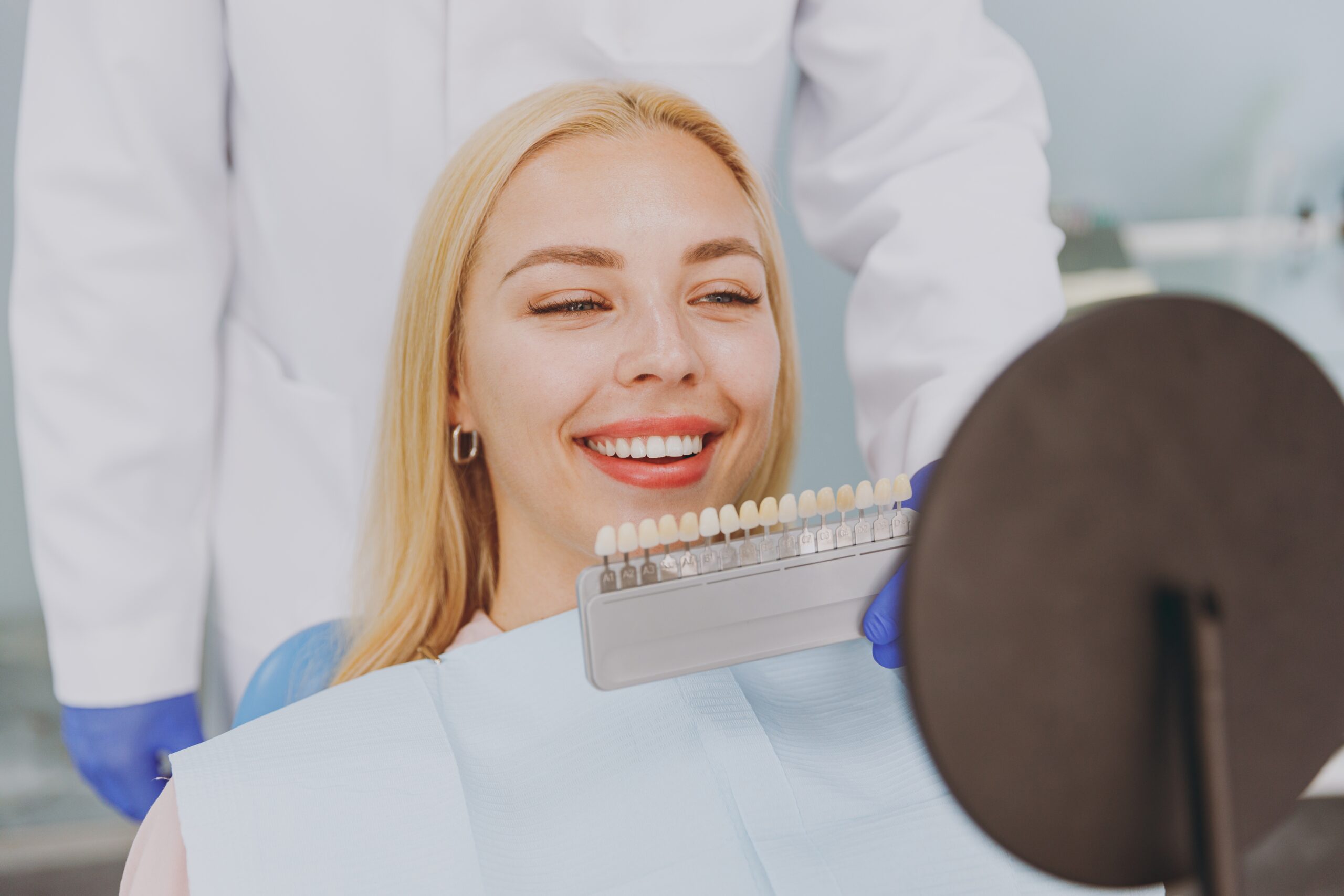 Close up young smiling happy caucasian woman choose veneers enamel color palette