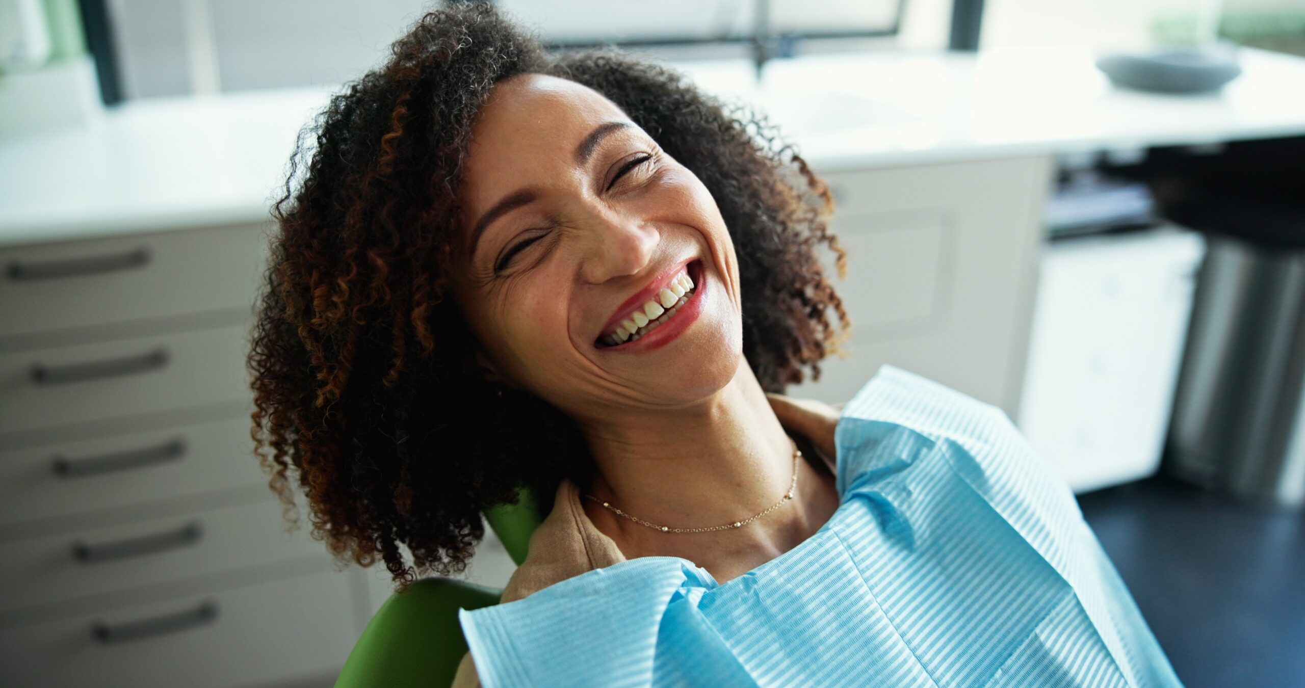 woman smiling in a dental chair, routine checkup