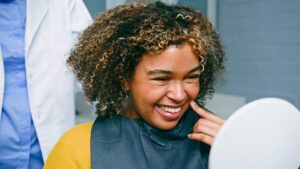 Smiling Woman Admiring Her Teeth in a Mirror During a Dental Appointment