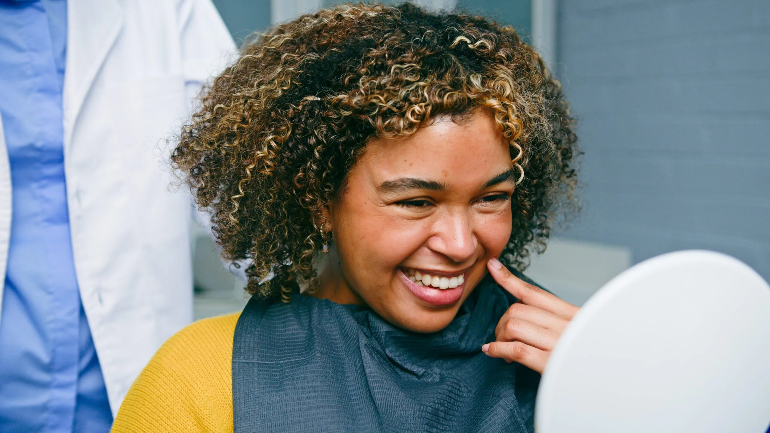 Smiling Woman Admiring Her Teeth in a Mirror During a Dental Appointment