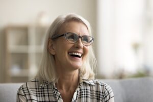 older woman smiling on a couch, new dental implants
