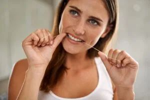 young woman flossing in the mirror