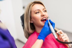 dentist in blue gloves polishing a dental crown